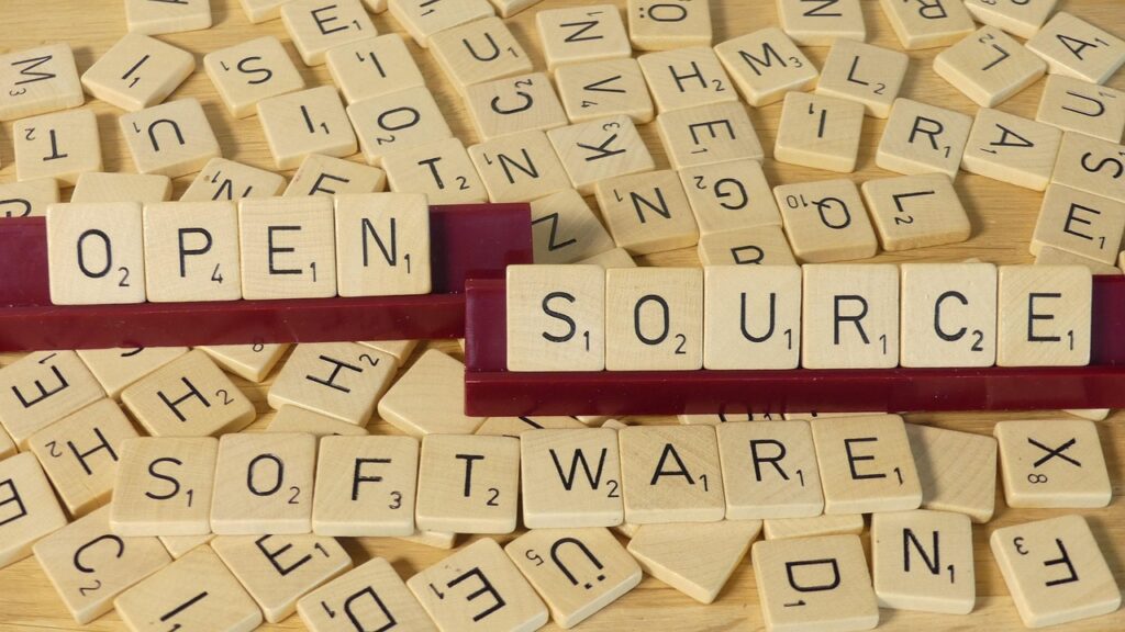 Ein Tisch voller Scrabble-Buchstaben. Auf zwei Ständern wurden die Worte "Open" und "Source" zusammengestellt.
